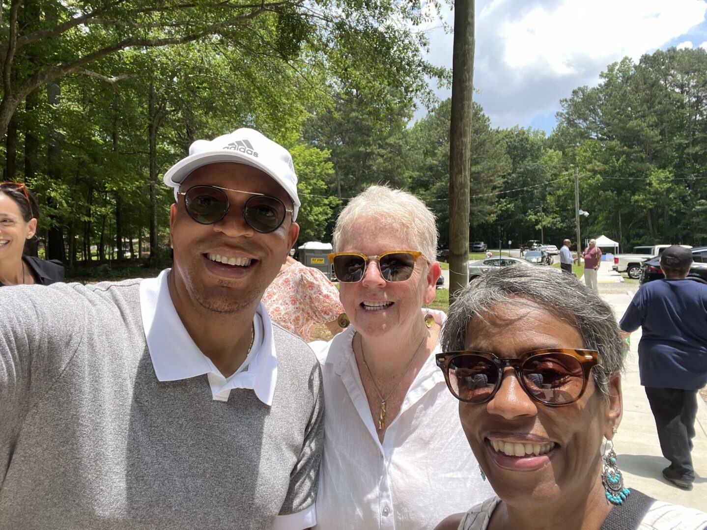 Three people posing for a picture in front of trees.