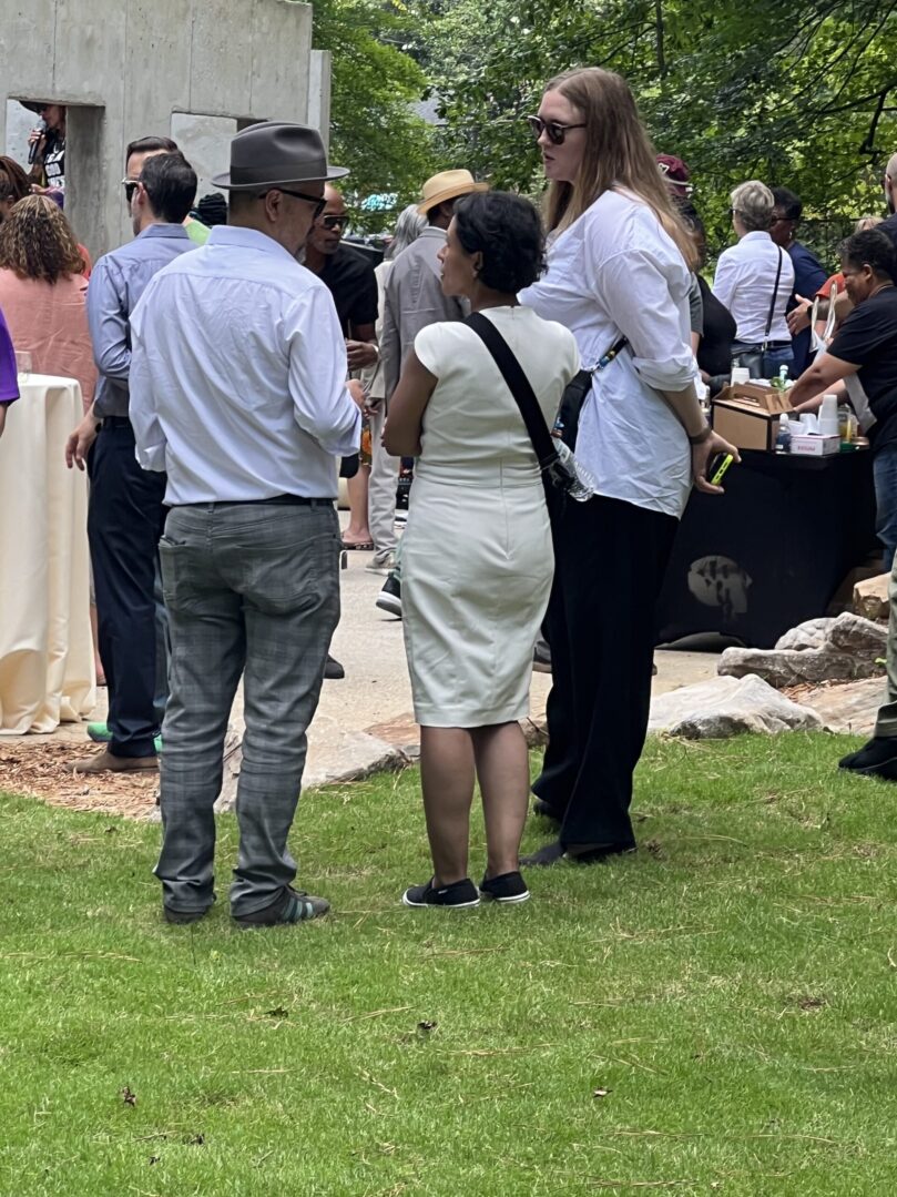 A group of people standing around in the grass.