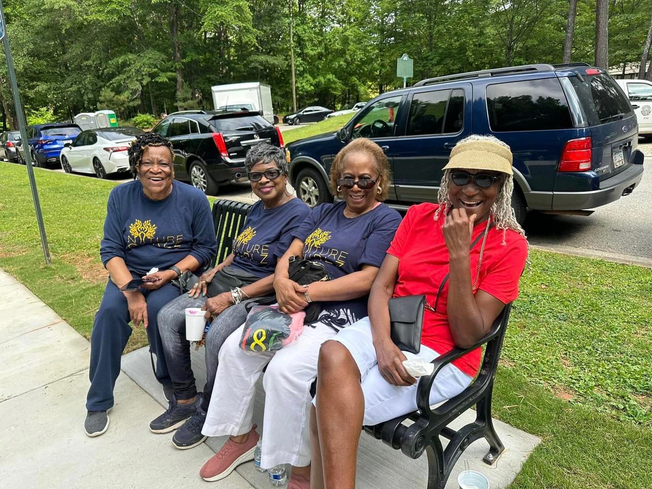 Four people sitting on a bench in the park.