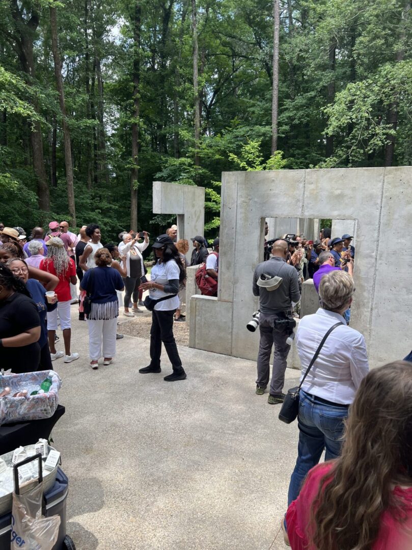 A group of people standing around in front of a wall.