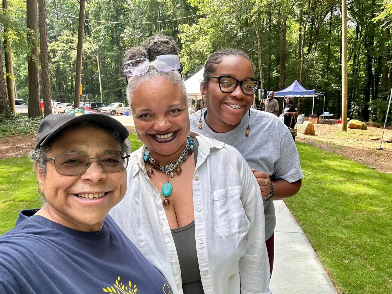 Three women standing next to each other on a sidewalk.