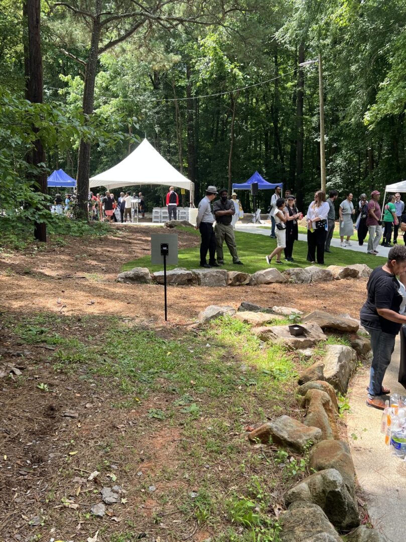 A group of people standing around in the woods.