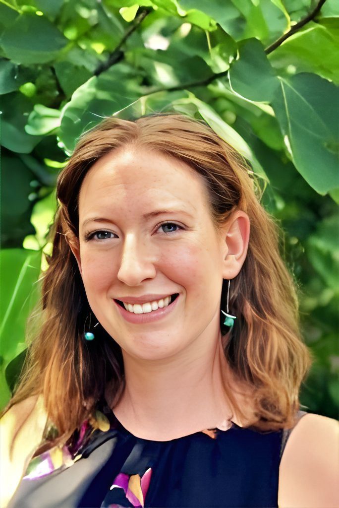 A woman with long red hair and green earrings.