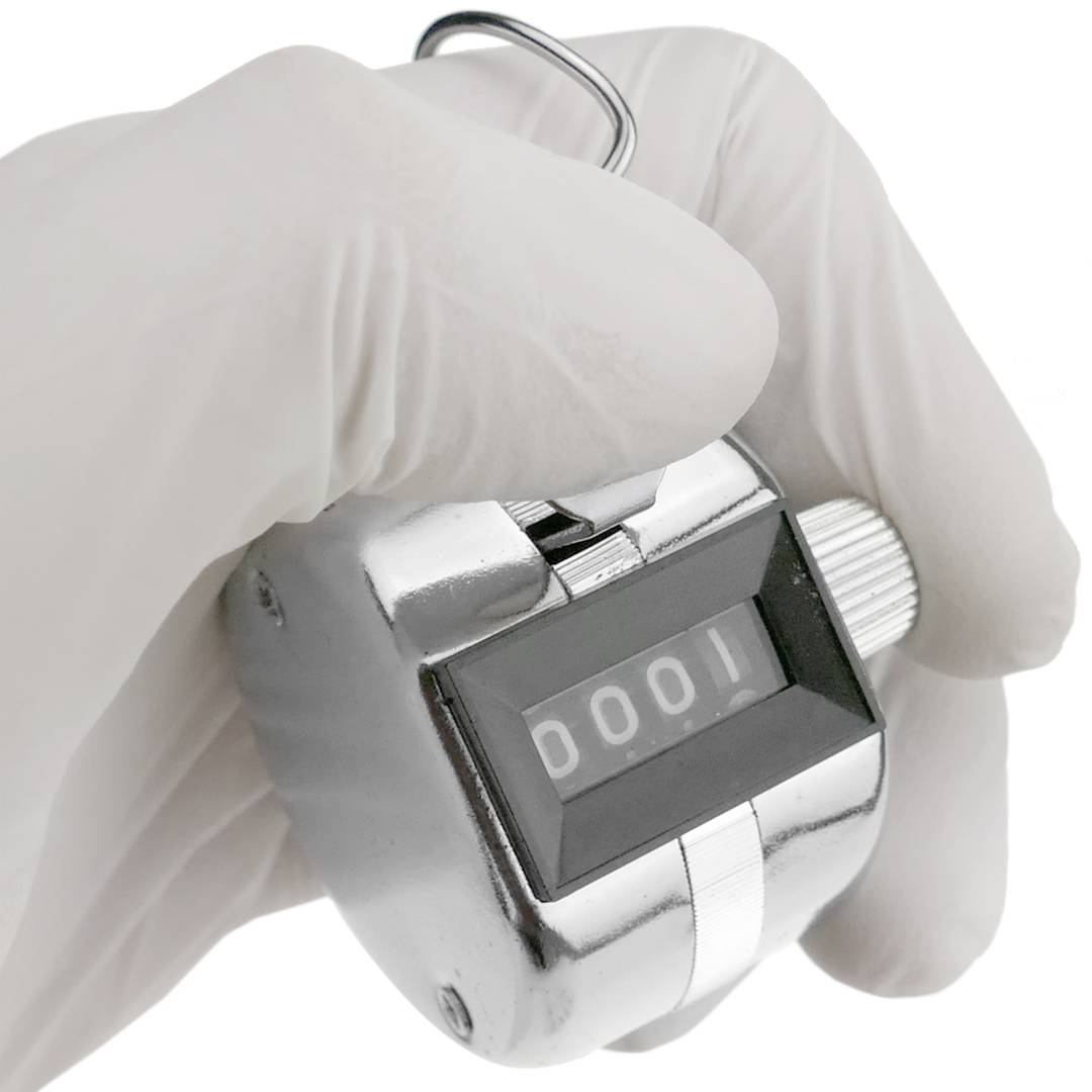 A hand is holding a silver tally counter.